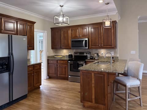 The kitchen features stainless appliances, granite counters, updated lighting, seating at the island, a separate area for a table/chairs, along with a formal dining room at the front of the home.